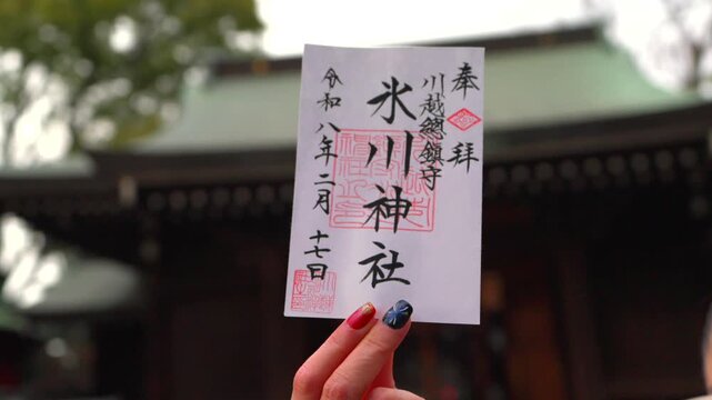 A woman visitor holds a Goshuin stamp at Kawagoe Hikawa Shrine a famous cultural and spiritual site in Japan showing traditional practice
