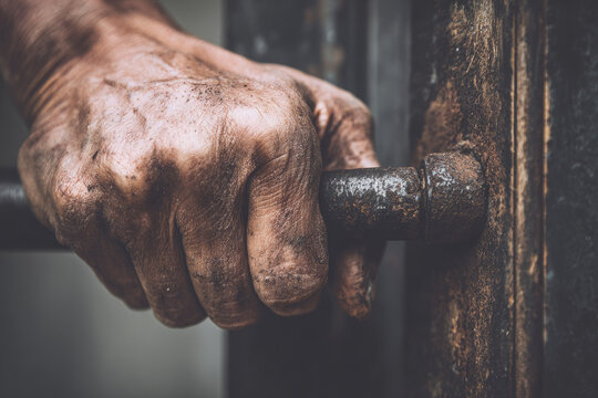 Flood barrier protects house as strong hand grips door handle showing resilience and determination in challenging conditions with weathered textures and earthy tones