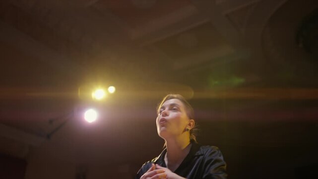Thoughtful performer rehearsing under warm stage lights in an empty theater, expressing emotion and focus while preparing for an intimate dramatic performance