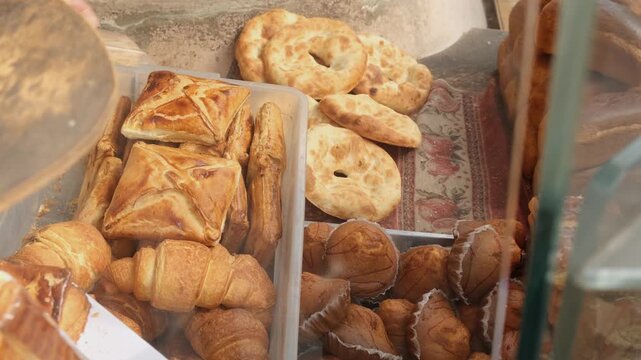 Baker hands pack several fresh eastern flatbreads into bag from bakery display. Sale of fresh bread baked in tonir stone on hot coals. Traditional national pita and khachapuri. Bakery business