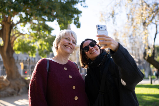 Two friends smiling and posing for a selfie in the park, showcasing their strong bond and friendship