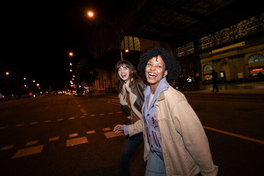 Friends laughing while crossing a city street at night