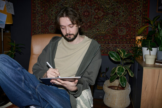 Freelancer drawing on graphics tablet in home office at night