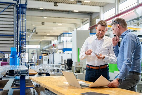 Engineers inspecting component at workbench in production hall