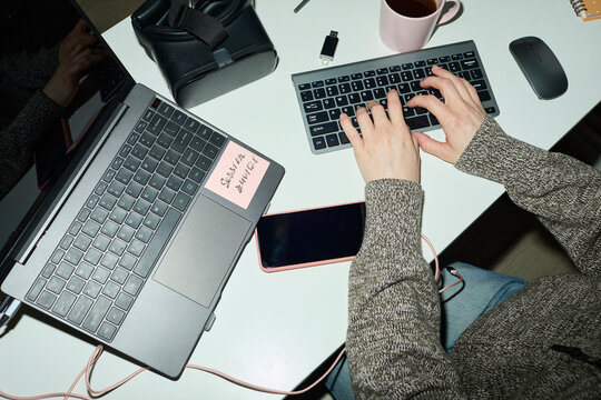 Programmer hands typing on keyboard at a busy modern desk