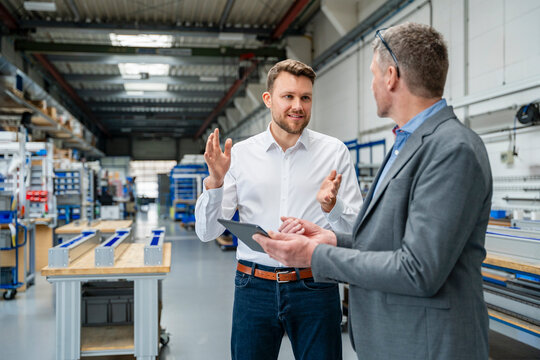Manager and engineer discussing plan with tablet in factory