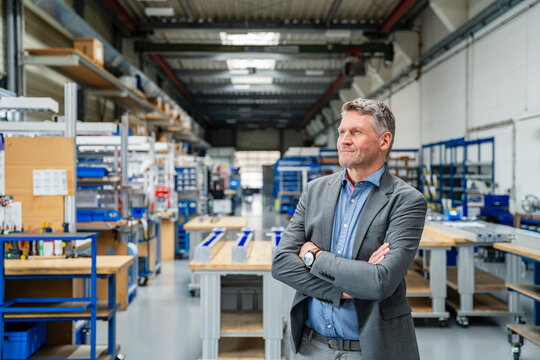 Satisfied manager with crossed arms in a production hall