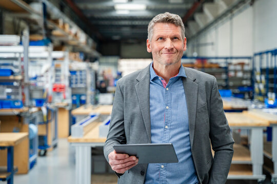 Satisfied manager holding a tablet in a production hall