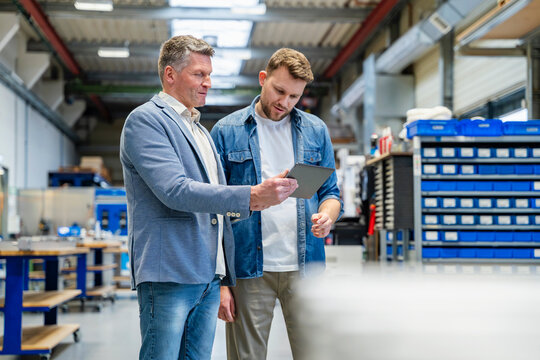 Manager and worker discussing production on a tablet indoors