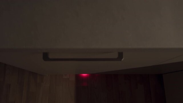 Elegant handle scene. Detailed closeup of tactile metal cabinet handle over red dot on hardwood floor