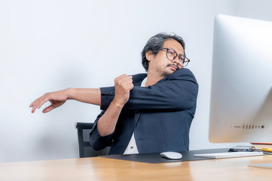 A young office worker feels shoulder and arm pain from prolonged sitting, highlighting work fatigue, strain, and the need for ergonomic care.