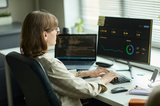 Programmer typing code on computer at office desk