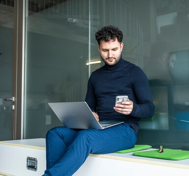 Businessman sitting in office reading message on mobile