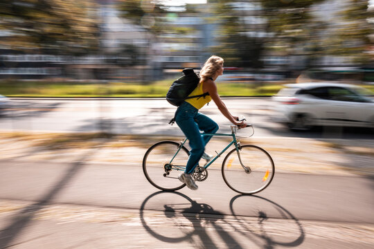 Woman commuting on bicycle in city street with panning blur