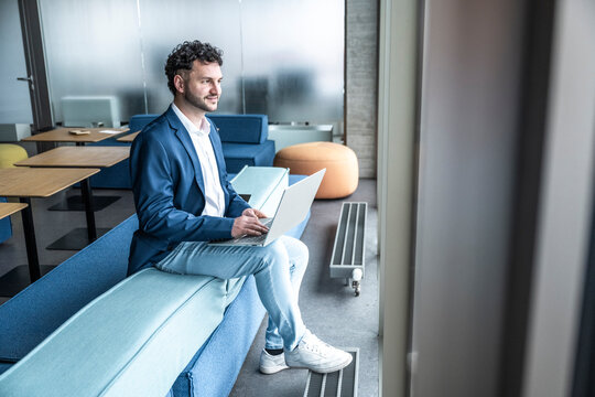Smiling businessman working on laptop in modern office