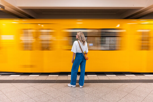 Passenger waiting for a yellow train at a Berlin subway station