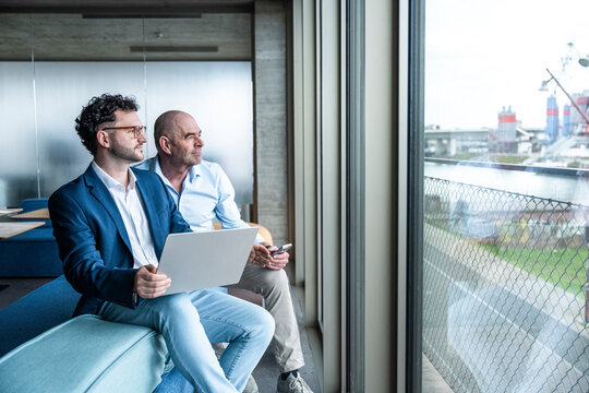 Businessman and colleague looking out of office window