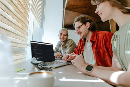 Programming team collaborating on code at office desk