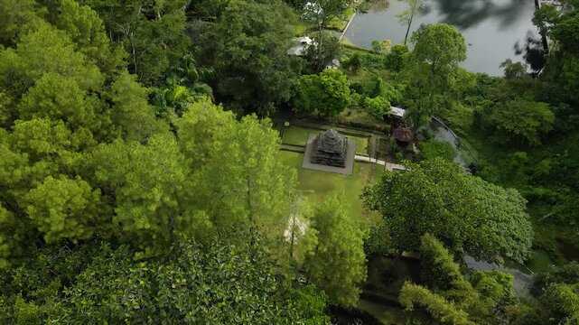 Aerial 4K view of an ancient stone temple in a lush tropical garden in Indonesia.