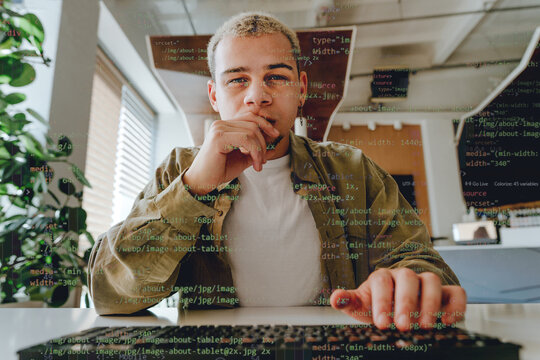 Focused programmer coding with digital overlay in modern office