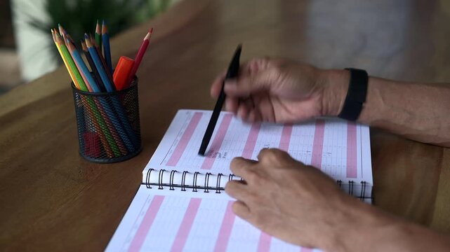 Asian male hand Asian male hand coloring a table on book and playing with black pen