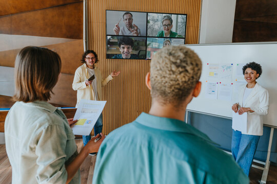 Business team discusses presentation in office video call