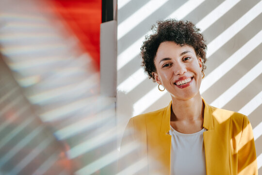Smiling businesswoman in yellow blazer at modern office window