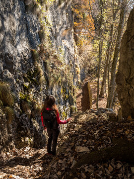 Outdoor lifestyle woman hiking a rocky autumn trail, exploring the scenic Forra del Lupo gorge in Trentino, Italy.