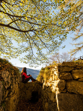 Autumn trekking lifestyle: Woman enjoying mountain views from historical World War I trenches at Forra del Lupo Trekking, Trentino, Italy, for travel and exploration.