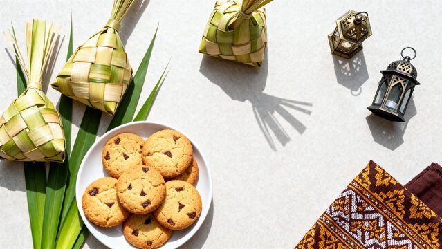 Top view of Hari Raya Idul Fitri flat lay with ketupat, cookies and lanterns on bright background with copy space