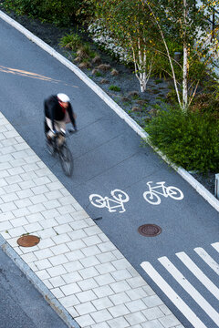 Overhead cyclist on bicycle in bike line on Stockholm Sweden pavement with markings showing motion and speed in urban commuting scene