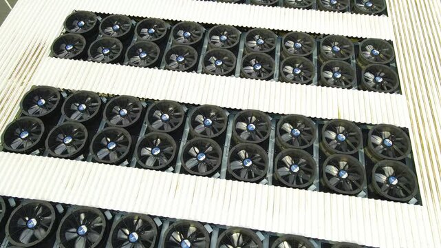 Aerial view of a massive cooling system on a data center rooftop, with countless industrial fans spinning to regulate temperature and prevent servers from overheating, ensuring data integrity
