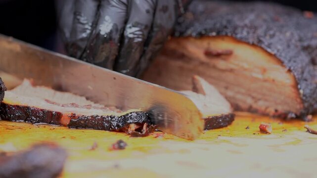 A person wearing black gloves prepares food on a cutting board
