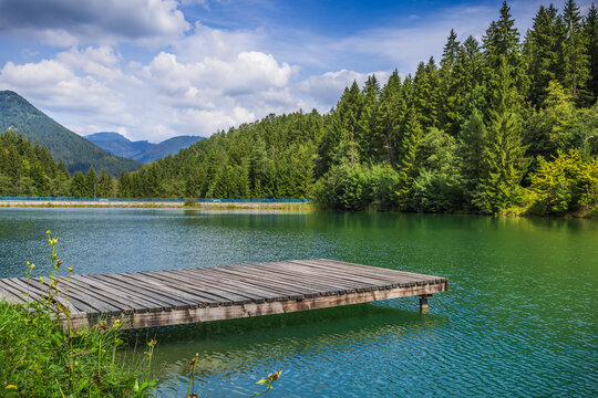 Wooden pontoon pier on a natural lake with mountains in background