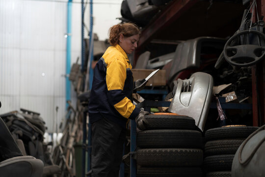 Used auto parts warehouse or Automotive spare parts warehouse. Female worker or Warehouse staff check recycling auto parts for verifying stock or inventory control