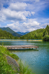 Fototapeta premium Wooden pontoon pier on a natural lake with mountains in background