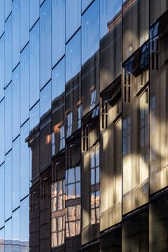 Reflected city textures on modern architecture facade building glass reflection windows forming abstract pattern geometry with layered brick balconies and glass