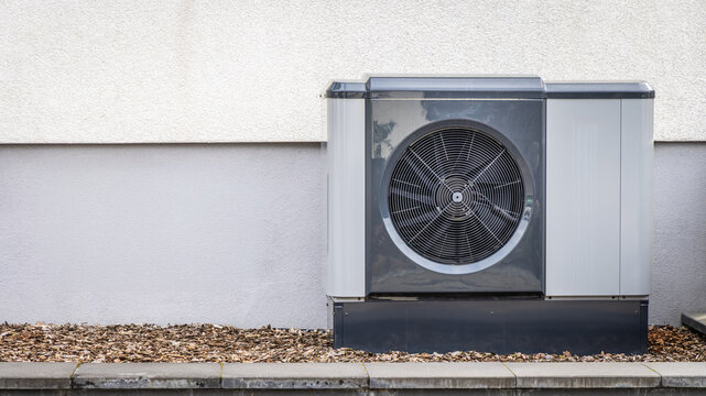 Modern air source heat pump installed on house wall