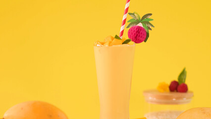 Tropical Mango Smoothie with Fruit Garnish on Bright Yellow Background © blueringmedia