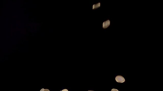 Saudi coins falling in slow motion against a black background, representing wealth and finance.