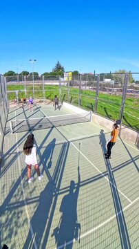 Four friends playing doubles pickleball match outdoors