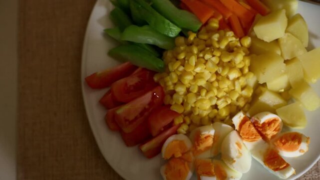 Top view handheld sliding shot view of various vegetable salad on white plate, healthy food