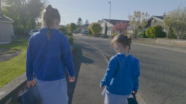 Two schoolgirls in uniforms walking to primary school