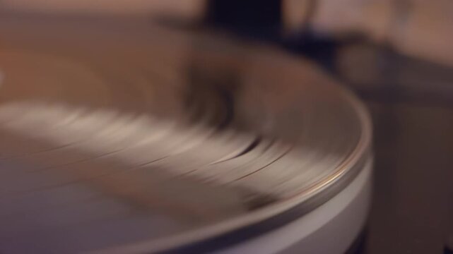 Close-up of a turntable needle gently gliding over a spinning vinyl record, showcasing the intricate details of the stylus and grooves in a cozy indoor setting
