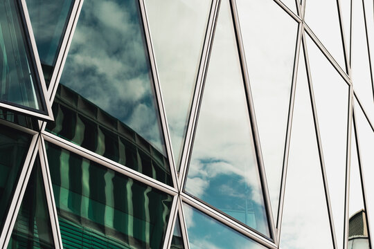 Triangles on a glass facade frame windows reflections with bold geometry and pattern creating modern abstract background for design layouts