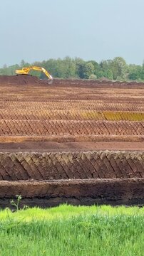 Peat extraction destroying moorland &ndash; drying peat fields at sunset - Trocknender Torf und Bagger zeigen den Eingriff in ein Moor&ouml;kosystem.