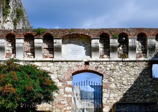 Historische Festungsmauer mit Gedenktafel und Rundbogentor am Castello di Brescia, Lombardei, Italien