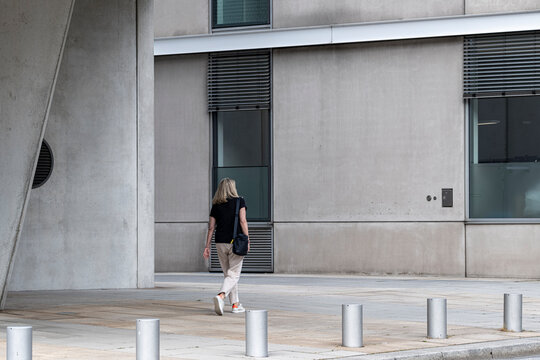 Solitude follows pedestrian on HafenCity walkway in Hamburg where modern architecture facade and minimalism shape an urban waterfront mood