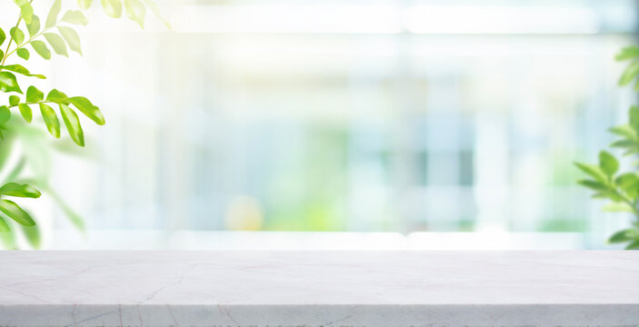 Selective focus.Elegance product display background with marble top on blur big window with fresh green leaf