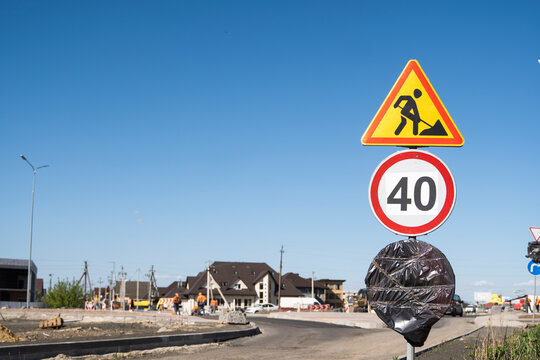 Road signs indicating construction and a 40 km/h speed limit while workers build new roads in a residential area